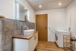 a bathroom with a sink and a washing machine at Ferienwohnung Schönhals in Herbstein +13 photos
