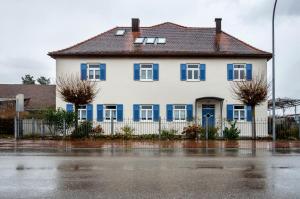 a white house with blue windows and a fence at Ferienwohnung mit privater Sauna in Gunzenhausen