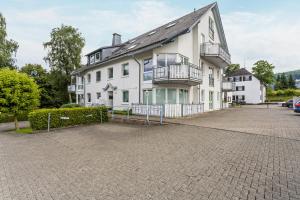 a large white house with a parking lot at Fewo Ricken am Kurpark in Willingen