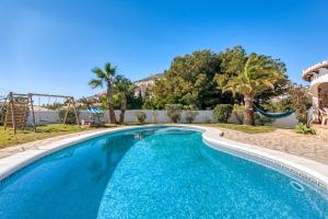 a swimming pool in a yard with palm trees at Entre Caballos in Cumbre del Sol
