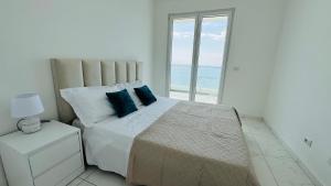 a white bedroom with a large bed with blue pillows at Eddy's Luxury Suites - Ilyonis in Shëngjin +18 photos