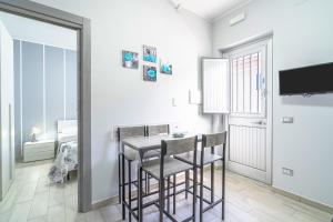 a dining room with a table and chairs and a television at Le Quattro Perle Apartments in Pachino