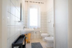 a bathroom with a sink and a toilet and a window at Villa Francesco P Terra in Orosei
