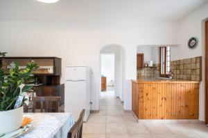 a kitchen with a table and a white refrigerator at Villa Francesco P Terra in Orosei +21 photos