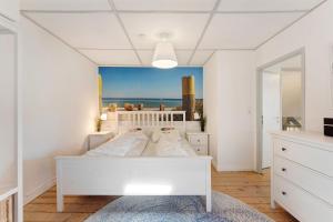 a white bedroom with a bed and a view of the ocean at Insel Hus in Fehmarn