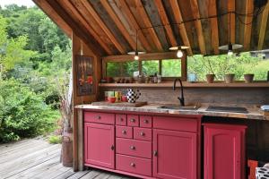 an outdoor kitchen with red cabinets and a sink at Cabane Myrtille in Arrien-en-Bethmale