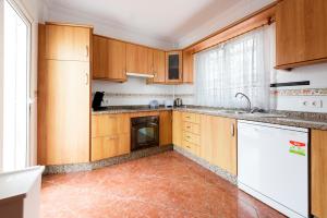 a kitchen with wooden cabinets and a white dishwasher at Villa Zoe in Nerja