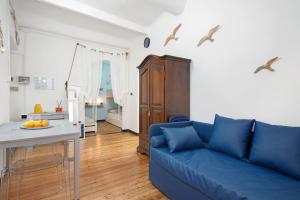a living room with a blue couch and a kitchen at Apartment baia del silenzio beach in Sestri Levante