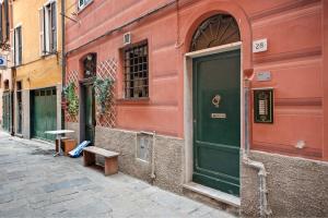 a red building with a green door and a bench at Apartment baia del silenzio beach in Sestri Levante