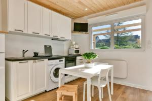 a kitchen with white cabinets and a white table at La Dune de Sable - Cavaro in Pornichet +7 photos
