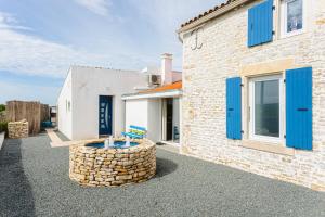 a stone house with blue shutters and a patio at Gîte Koala in Marans