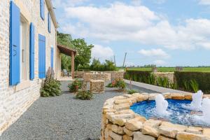 a backyard with a water fountain in a stone wall at Gîte Koala in Marans