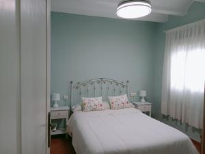 a bedroom with a white bed with two tables and a window at Casa Rural San Antón in Quesa