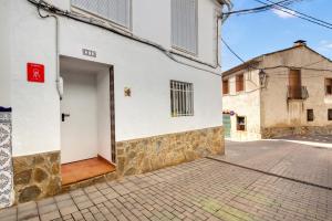 a white building with a door on a street at Casa Rural San Antón in Quesa