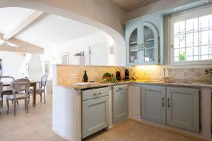 a kitchen with blue cabinets and a dining room at Golfvilla Riviera in Grimaud
