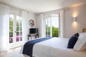 a bedroom with a large white bed and windows at Golfvilla Riviera in Grimaud +24 photos