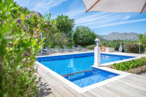 a swimming pool with chairs and an umbrella at Can Negri - Almadraba in El Port