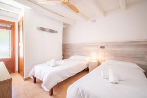 two beds in a room with white sheets at Can Negri - Almadraba in El Port +20 photos