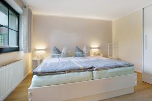 a white bedroom with a large bed with blue sheets at Ferienwohnung To Hus in Putbus
