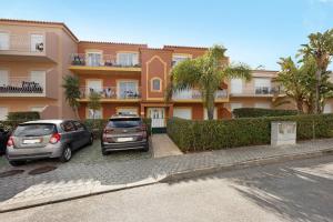 two cars parked in a parking lot in front of a building at Palmeiras Reais 110 in Portimão