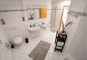 a white bathroom with two sinks and a mirror at Wohnung im Rheintal in Küssaberg +8 photos