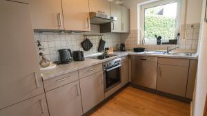 a kitchen with white cabinets and a sink and a window at Wohnung im Rheintal in Küssaberg