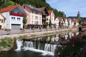 a river in a town with a waterfall at Ferienwohnungen Beilerstädtle in Oppenau