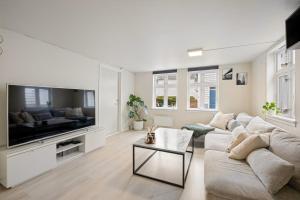a white living room with a couch and a tv at Harmony Apartments - Stavanger Sentrum 2 in Stavanger