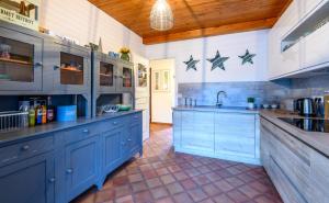 a large kitchen with blue cabinets and a sink at Chalet du cret in Lathuile +6 photos