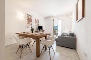 a living room with a wooden table and white chairs at Comfort Appartamento Le Cementine in Tremosine Sul Garda