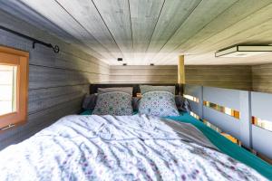 a bed in a small room with a wooden wall at La Cabane Perchée in Vert