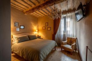a bedroom with a bed and a chair and a window at L'imbrunire in Campiglia dʼOrcia