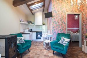 a living room with green chairs and a kitchen at La Caseta De Laura in Arzúa
