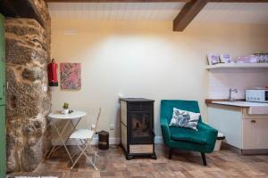 a living room with a green chair and a stove at La Caseta De Laura in Arzúa +12 photos