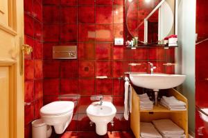 a red tiled bathroom with a toilet and a sink at Appartamento Cesa Wanker in Ortisei +16 photos