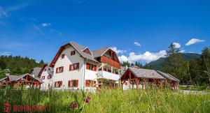 a large white building with red roofs in a field at Apartments Bohinjskih 7 in Bohinj