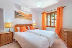 a bedroom with a bed with orange curtains and a window at Es Cantó in Cala Llombards +13 photos
