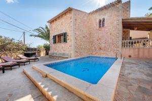 an outdoor swimming pool in front of a house at Es Cantó in Cala Llombards