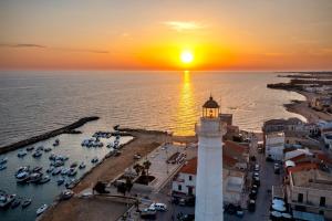 a lighthouse in a harbor with a sunset at Vista Mare in Santa Croce Camerina +14 photos