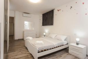 a white bedroom with a white bed and white cabinets at Villetta farfalle in Sarroch
