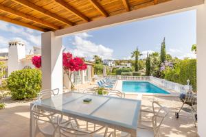 a patio with a glass table and chairs next to a swimming pool at Villa Andes in Benissa