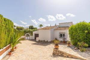 a white house with a courtyard and trees at Villa Andes in Benissa