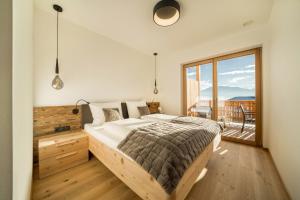 a bedroom with a large bed and a balcony at Apt Eiche - Nockerhof in Andrian