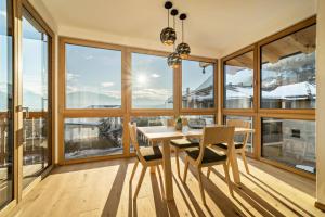 a dining room with a table and chairs and large windows at Apt Eiche - Nockerhof in Andrian