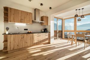 a kitchen with wooden cabinets and a dining room with a table at Apt Eiche - Nockerhof in Andrian +18 photos