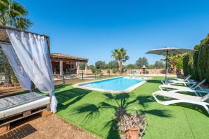 a swimming pool with lawn chairs and an umbrella at Ses Oliveres in Campos