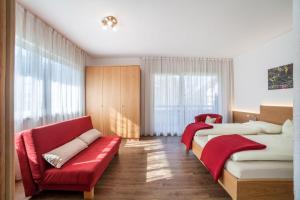 a bedroom with two beds and a red couch at Schnitzer Ferienwohnung Hagebutte in Rablà