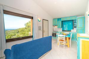 a living room with a blue couch and a kitchen with a table at Conchiglia Blu in Barrabisa