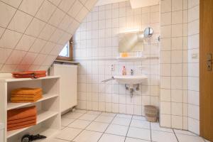 a white tiled bathroom with a sink and a shower at Ferienwohnung Nr 2 in Deggenhausertal