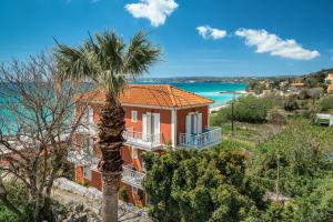 a house with a palm tree in front of the ocean at Angela partial sea view 8 in Kefallonia